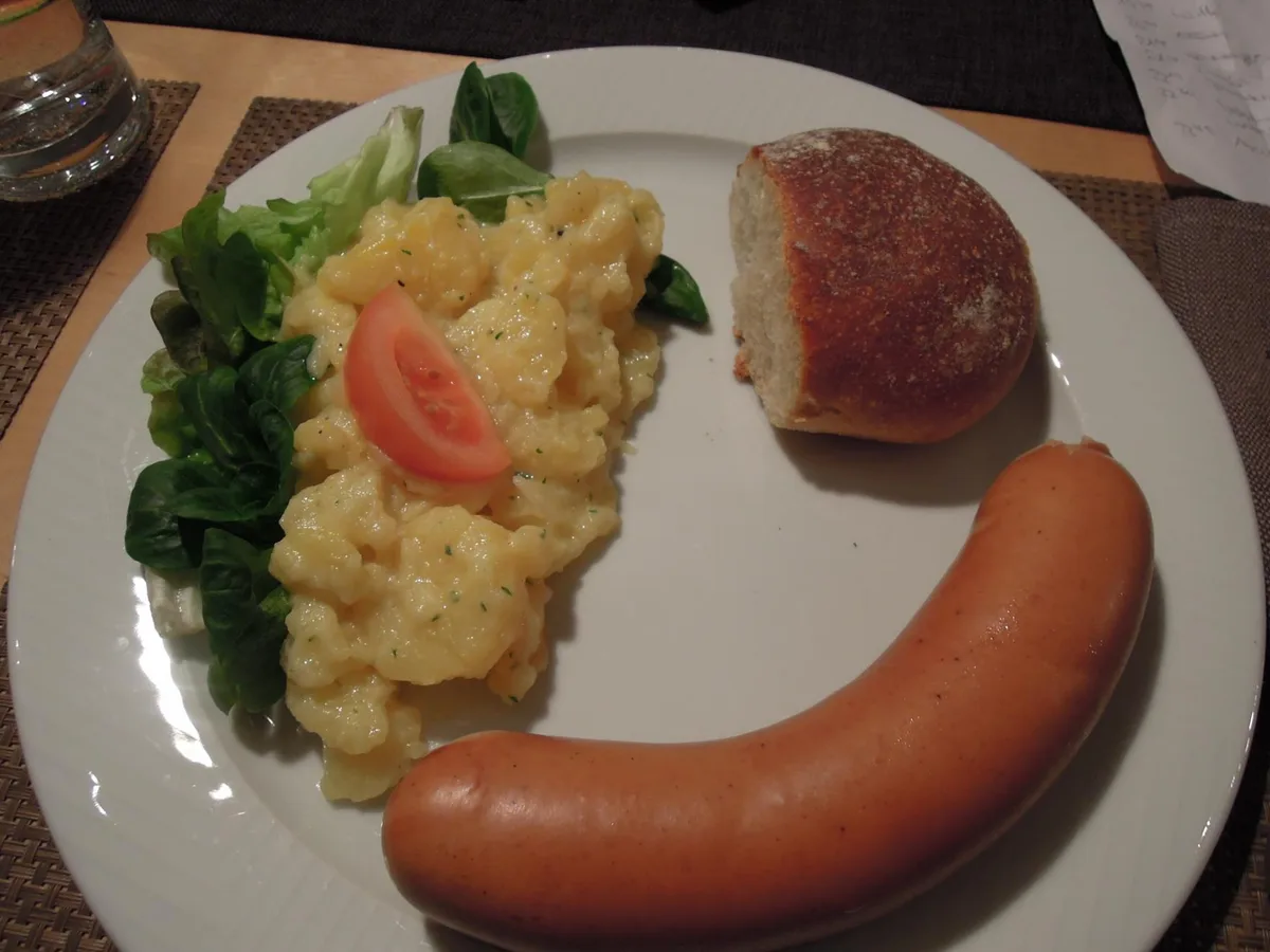 Wurst auf einem Teller mit Salat und Brot.